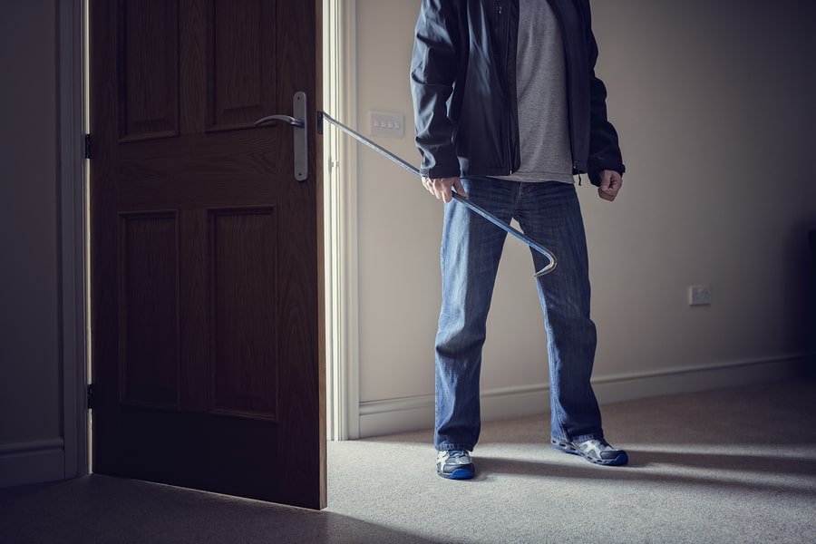 Burglar committing a burglary crime in a house with a crowbar